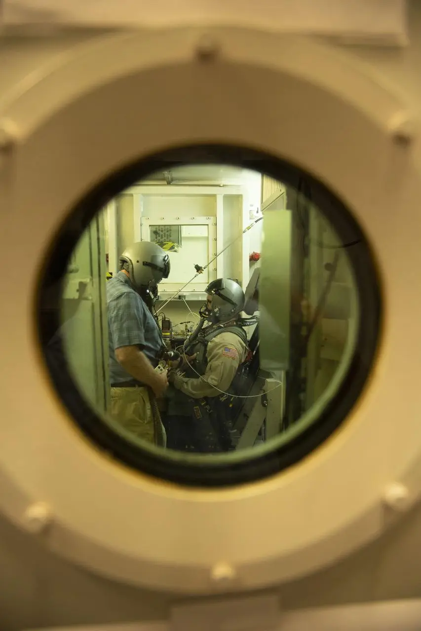 Test volunteer and technician seen through the window of a hypobaric chamber