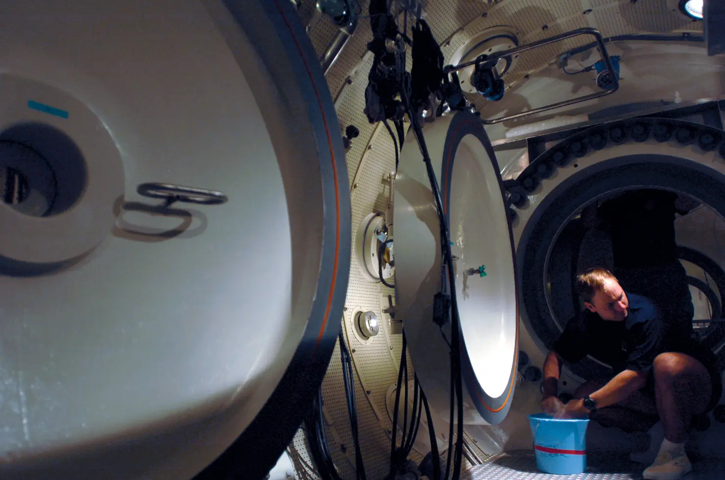 Technician cleaning the interior of a naval experimental compression chamber